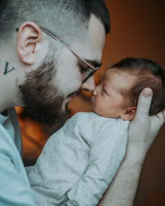 Papa tenant son bébé face à lui et lui touchant le nez avec le sien
