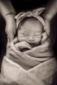 Une maman tenant son bébé qui est enveloppée